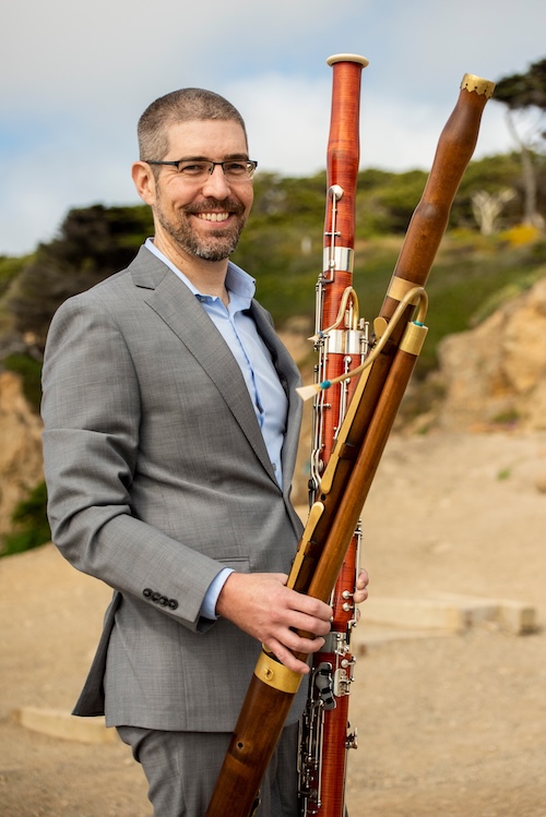 Dr. David A. Wells outdoors, holding modern and Baroque bassoons
