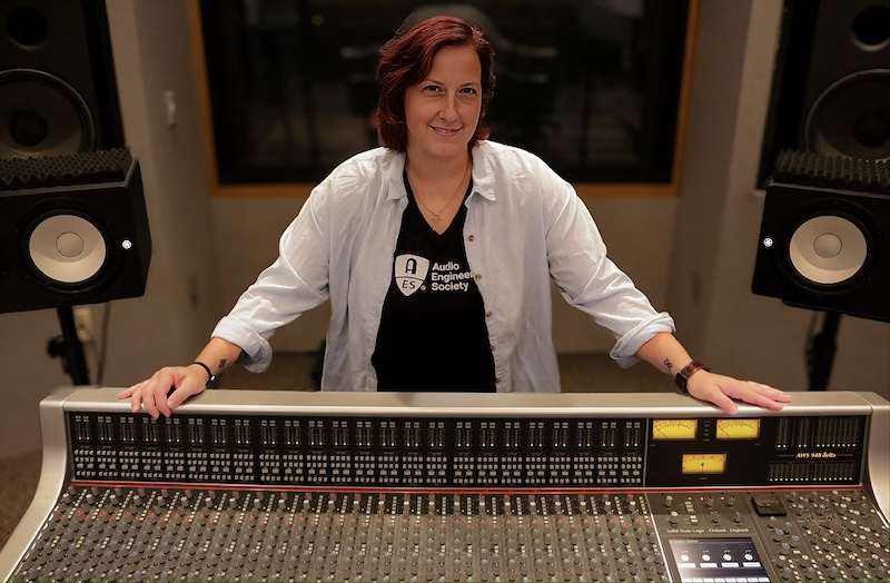 Liz May poses with a sound mixing board