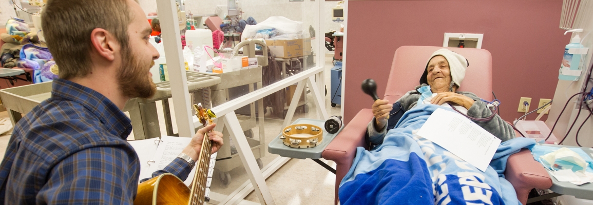 Hayes School of Music music therapy student playing guitar for patient